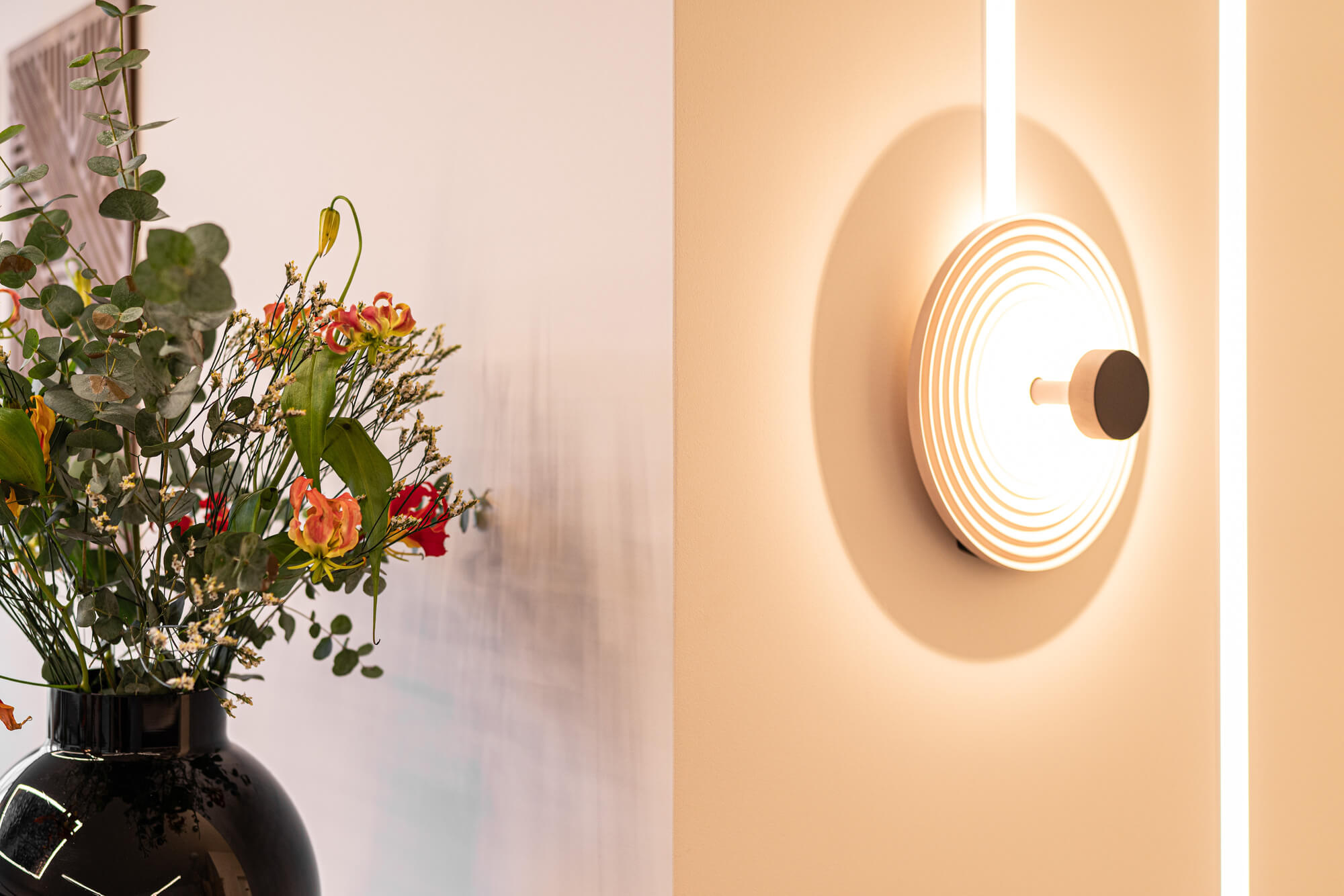 Blumen und Wandleuchte im modernen Empfangsbereich der Zahnarztpraxis Feyo Dent