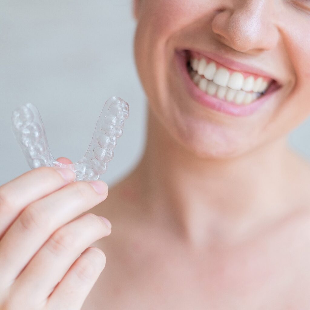 Patientin hält transparente Zahnschiene für Aligner-Behandlung